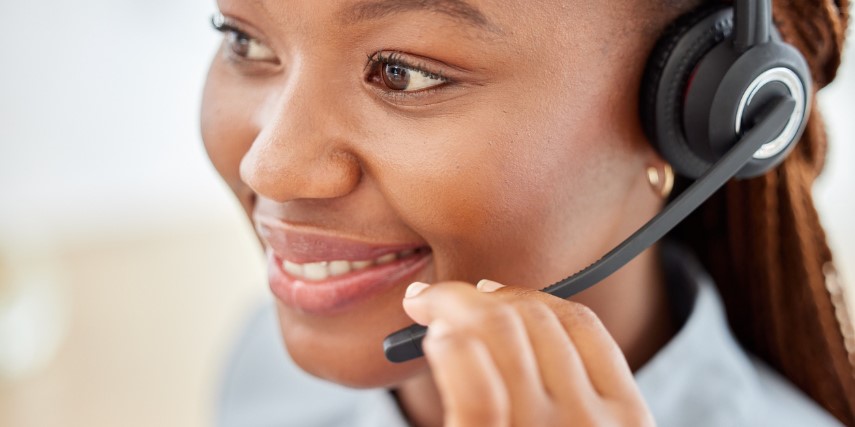 Young woman smiles as she holds the mouthpiece of her headset.