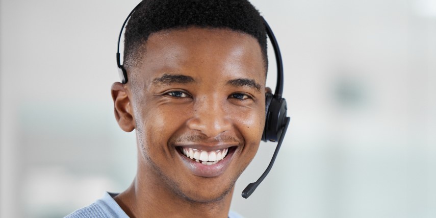 A young man wearing a headset smiles. 