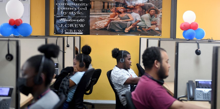 A side view of a row of customer service agents, all seated at their desks and focused on their work. 